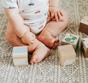 Baby playing with wooden blocks in the nursery room