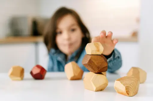 Child stacking wooden blocks at a table